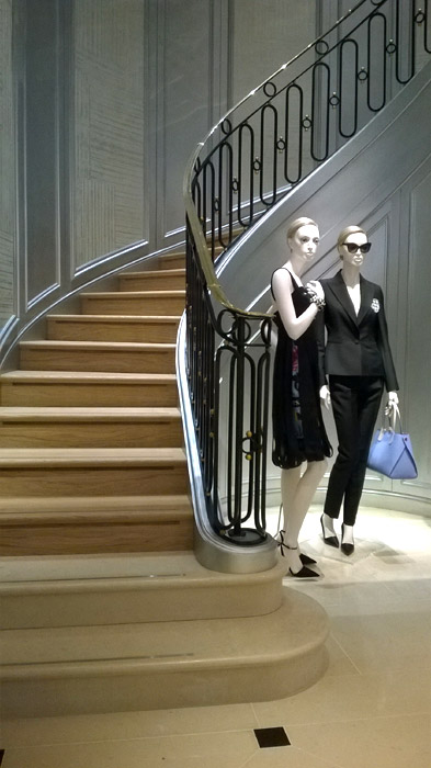 Christian Dior shop mannequins standing next to metal stair balustrade in London shop.