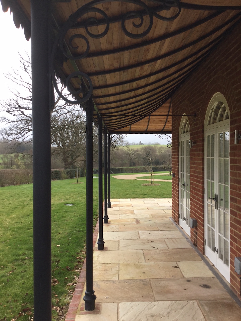 Traditional Victorian Style Ironwork Column Verandah with Custom forged steel scroll Brackets and curved roof frame which has been lined with tongue and groove boards and finished in lead with a decorative scalloped edge