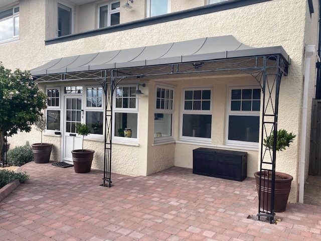 Trellis Style Regency Veranda Ironwork with a Straight Unhipped Glazing Bar Roof which has Glass Panels over French Doors and Zinc Galvanised Infill Sheets to created a shaded outdoor living space 